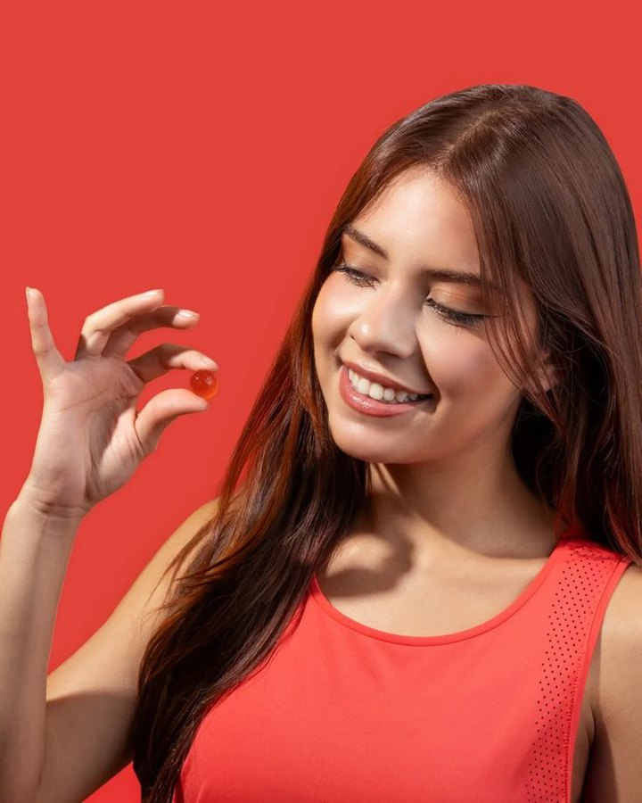 A woman smiling in a coral top